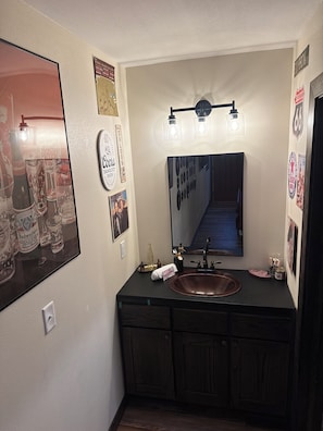 A bathroom with a large mirror, a sink, and a vanity with cabinets.