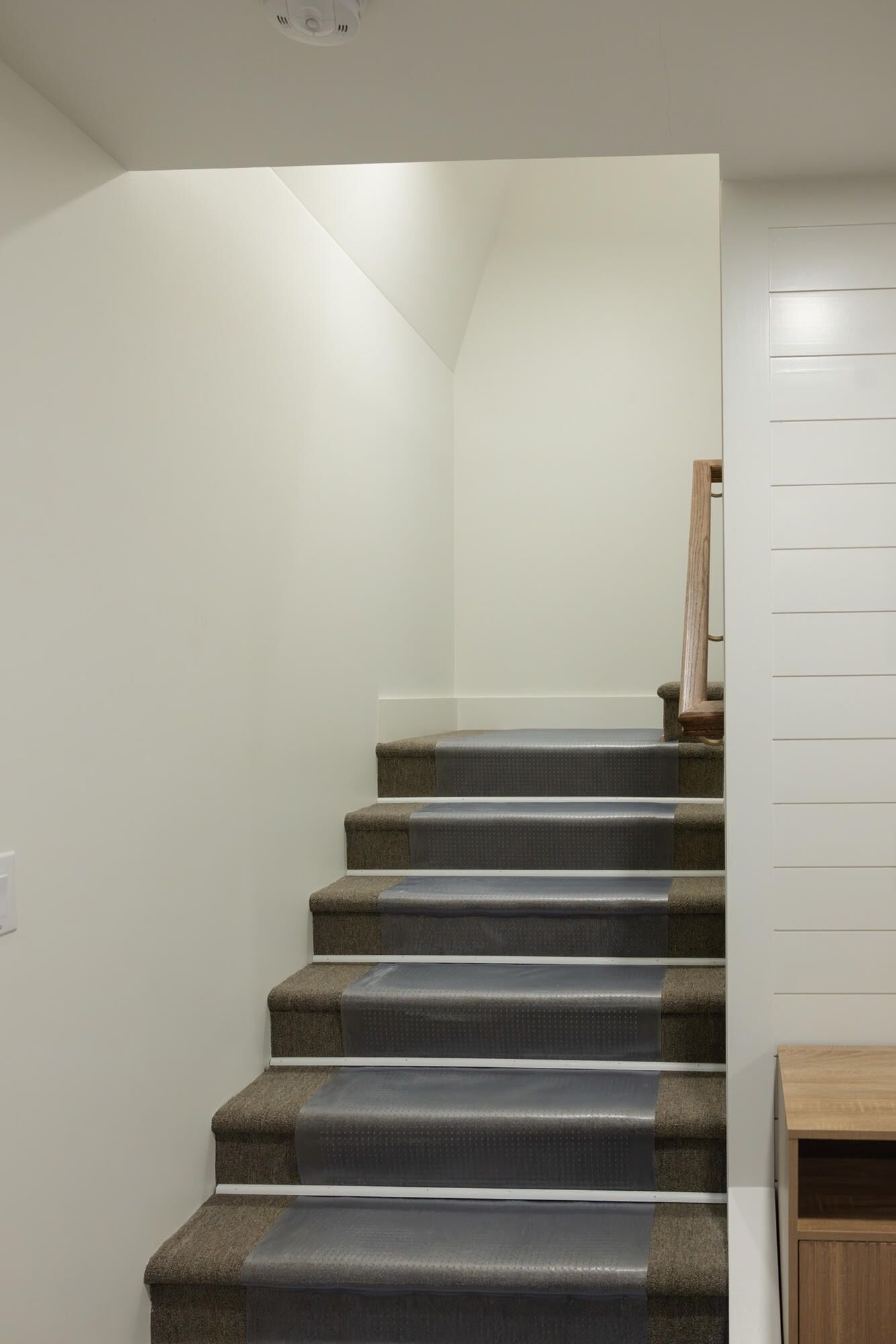 Una escalera con peldaños alfombrados y barandilla de madera.
