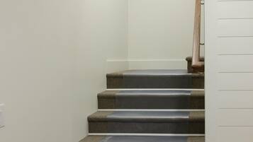 Una escalera con peldaños alfombrados y barandilla de madera.