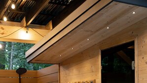 A wooden sauna room with a wooden bench, a towel rack, and a shower head.