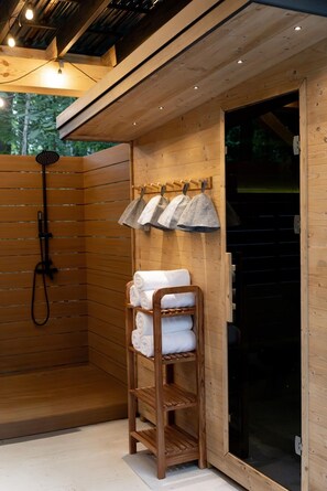 A wooden sauna room with a wooden bench, a towel rack, and a shower head.