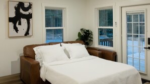 A bedroom with a bed, a ceiling fan, a window, and a door.