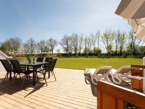 A patio with a table and chairs, a wooden deck, and a view of a grassy area with trees. - Reiterhof Rickert Glücksklee by Interhome (Bannesdorf)