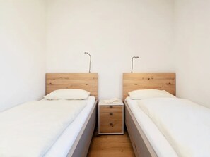 A simple room with two single beds, each with a wooden headboard and white bedding. - Reiterhof Rickert Glücksklee by Interhome (Bannesdorf)