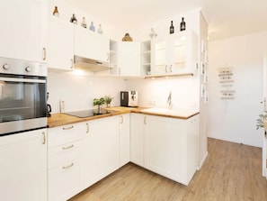 A modern kitchen with white cabinets, a stainless steel oven, and a coffee machine. - Meeresblick Ankerplatz 84 by Interhome (Kellenhusen)