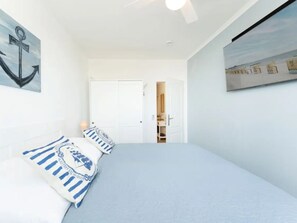 A bedroom with a bed, pillows, a door, and a wall with a painting. - Meeresblick Ankerplatz 84 by Interhome (Kellenhusen)