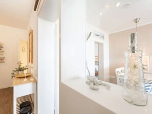 A modern bathroom with a white countertop, a glass bottle, and a mirror. - Meeresblick Ankerplatz 84 by Interhome (Kellenhusen)