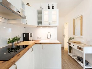 A modern kitchen with white cabinets, a wooden countertop, a built-in oven, and a sink. - Meeresblick Ankerplatz 84 by Interhome (Kellenhusen)