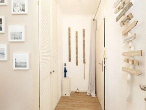 A hallway with a wooden floor, white doors, and a wall with directional signs. - Meeresblick Ankerplatz 84 by Interhome (Kellenhusen)