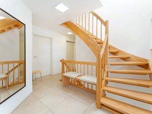 A modern interior with a wooden staircase, a small seating area, and a large mirror. - am Seeufer by Interhome (Malente-Gremsmühlen)