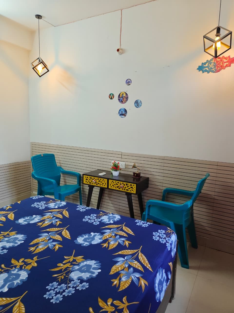 A room with a bed, two chairs, a small table, and wall decorations.