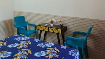A room with a bed, two chairs, a small table, and wall decorations.