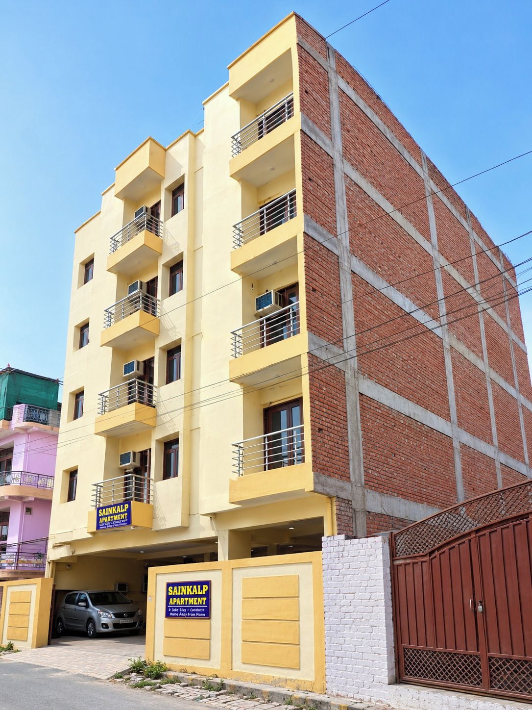 Un edificio de varios pisos con fachadas de ladrillo amarillo y rojo, varios balcones y una entrada porticada.