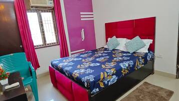 A bedroom with a bed, a desk, a chair, a window with curtains, and a ceiling fan.