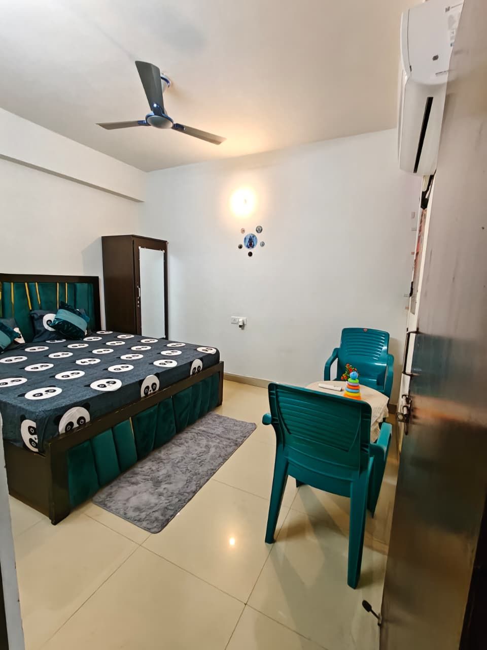 Ein Schlafzimmer mit einem Bett, einem Schreibtisch, einem Stuhl, einem Deckenventilator und einer Klimaanlage.