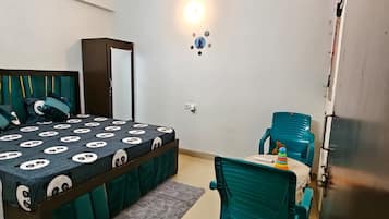 Ein Schlafzimmer mit einem Bett, einem Schreibtisch, einem Stuhl, einem Deckenventilator und einer Klimaanlage.
