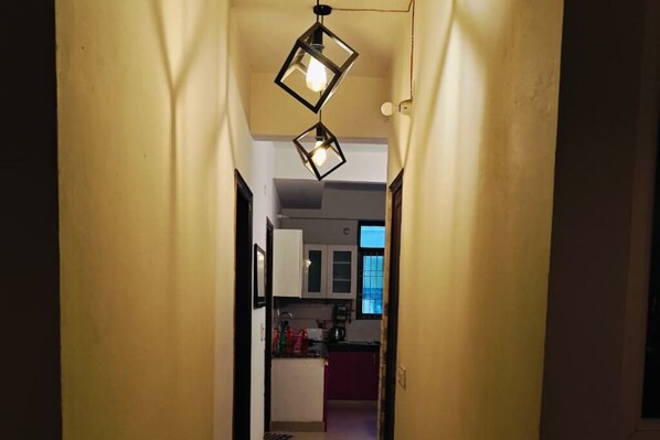 A narrow hallway leading to a kitchen area with cabinets and a window.