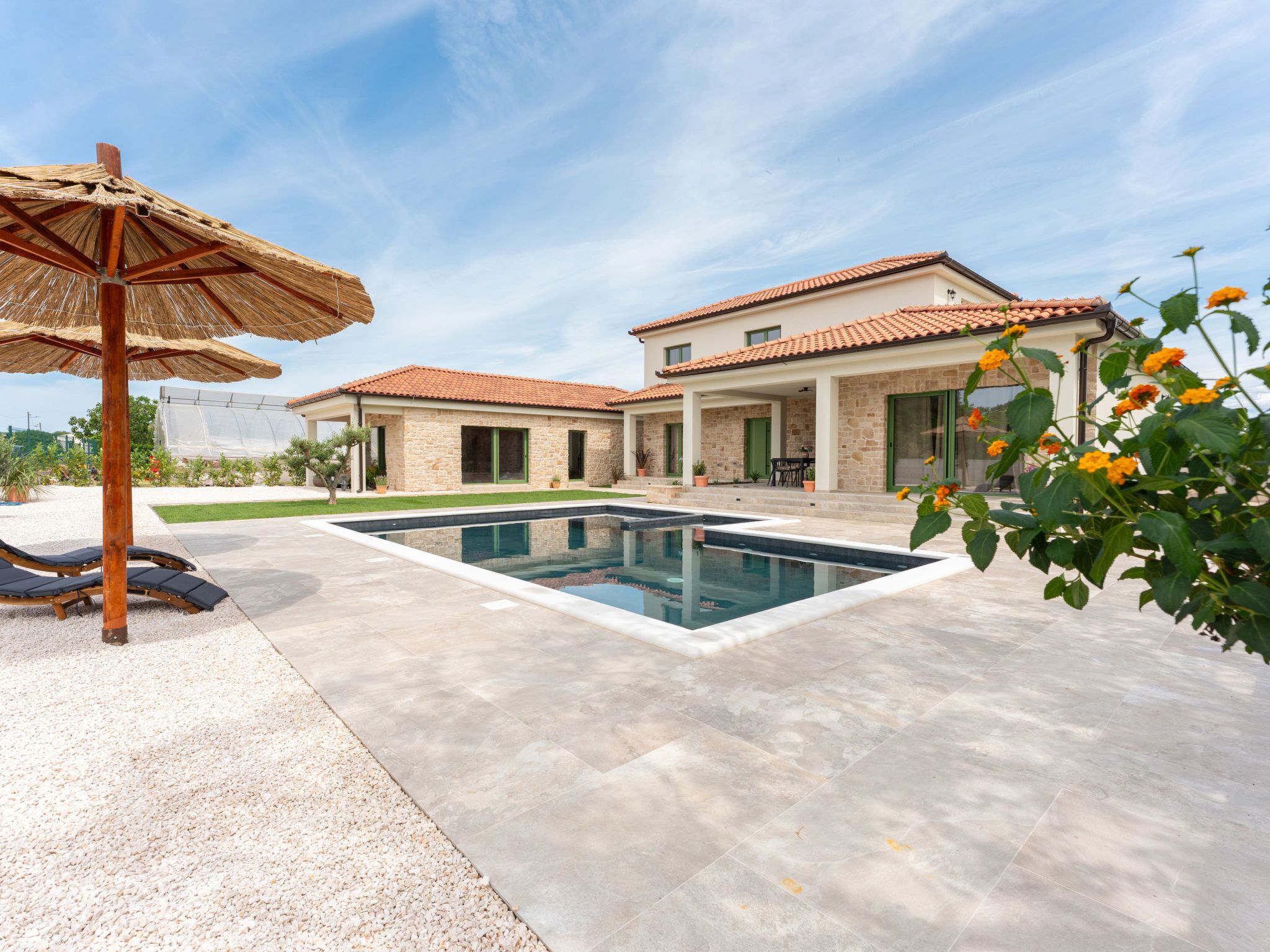 Una casa moderna con piscina, mobiliario de exterior y jardín.
