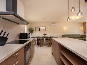 A modern kitchen with a central island, a dining area, and a sofa in a living space. - Beautiful Villa Lorna with pool by Interhome (Biograd na Moru)