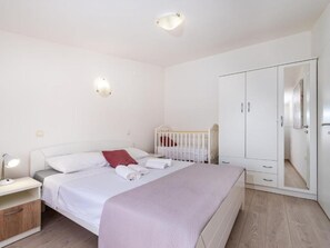 A bedroom with a bed, bedside table, lamp, wardrobe, and a crib. - Holiday Home Tonka with pool by Interhome (Donje Rastane)