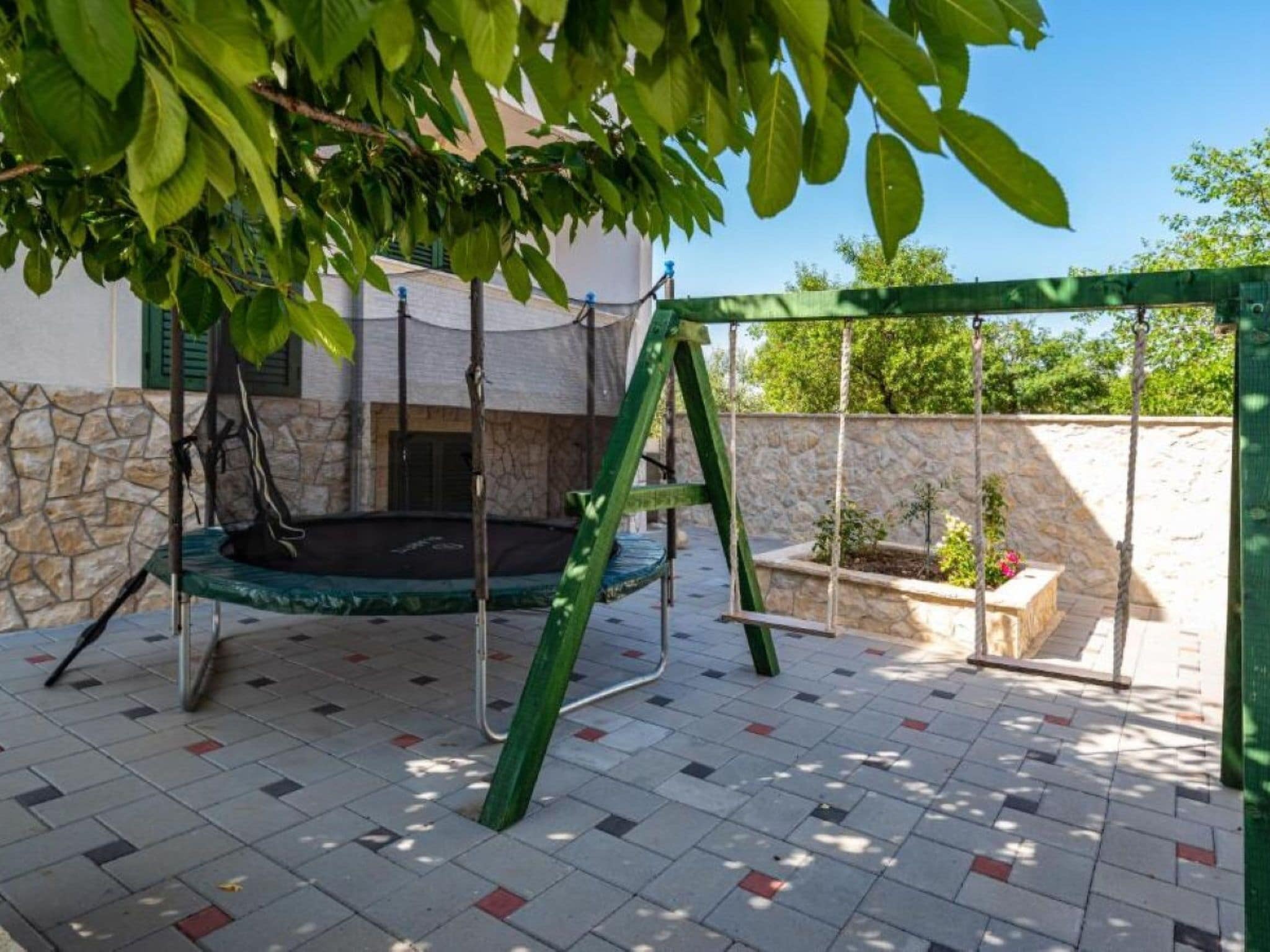 Eine Terrasse mit Schaukel, Steinmauer und Fliesenboden.