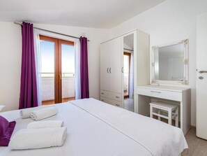 Hotellihuone, jossa on sänky, työpöytä ja kylpyhuone, jotka näkyvät avoimesta ovesta.