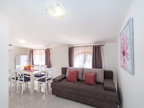 Un espace de vie comprenant un canapé, une table à manger avec des chaises et un tableau accroché au mur.