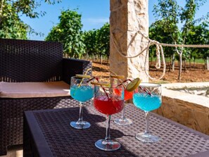 Three glasses of cocktails on a woven table with a wicker chair and a rope in the background. - Apartment Lara 2+2 by Interhome (Donje Rastane)