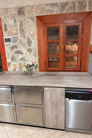 A kitchen with a stone wall, wooden cabinets, and stainless steel appliances. - Apartment Lara 2+2 by Interhome (Donje Rastane)
