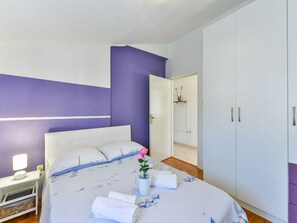 A bedroom with a bed, a nightstand, a dresser, and a door leading to a bathroom. - Holiday Home Marina with pool by Interhome (Sukošan)
