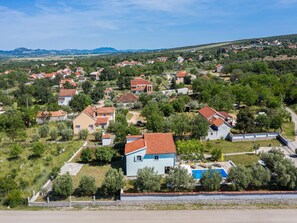 A residential area with houses, a swimming pool, and a road in the foreground. - Holiday Home Marina with pool by Interhome (Sukošan)