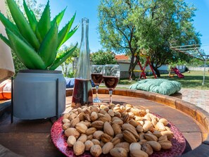 A table with a plate of almonds, two wine glasses, and a bottle of wine. - Holiday Home Marina with pool by Interhome (Sukošan)