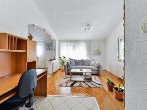 A living room with a sofa, coffee table, and a desk with a chair. There are potted plants and a radiator. - Holiday Home Marina with pool by Interhome (Sukošan)
