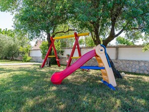 Ein Spielplatz mit einer roten Rutsche und einer Schaukel mit gelben und roten Elementen.