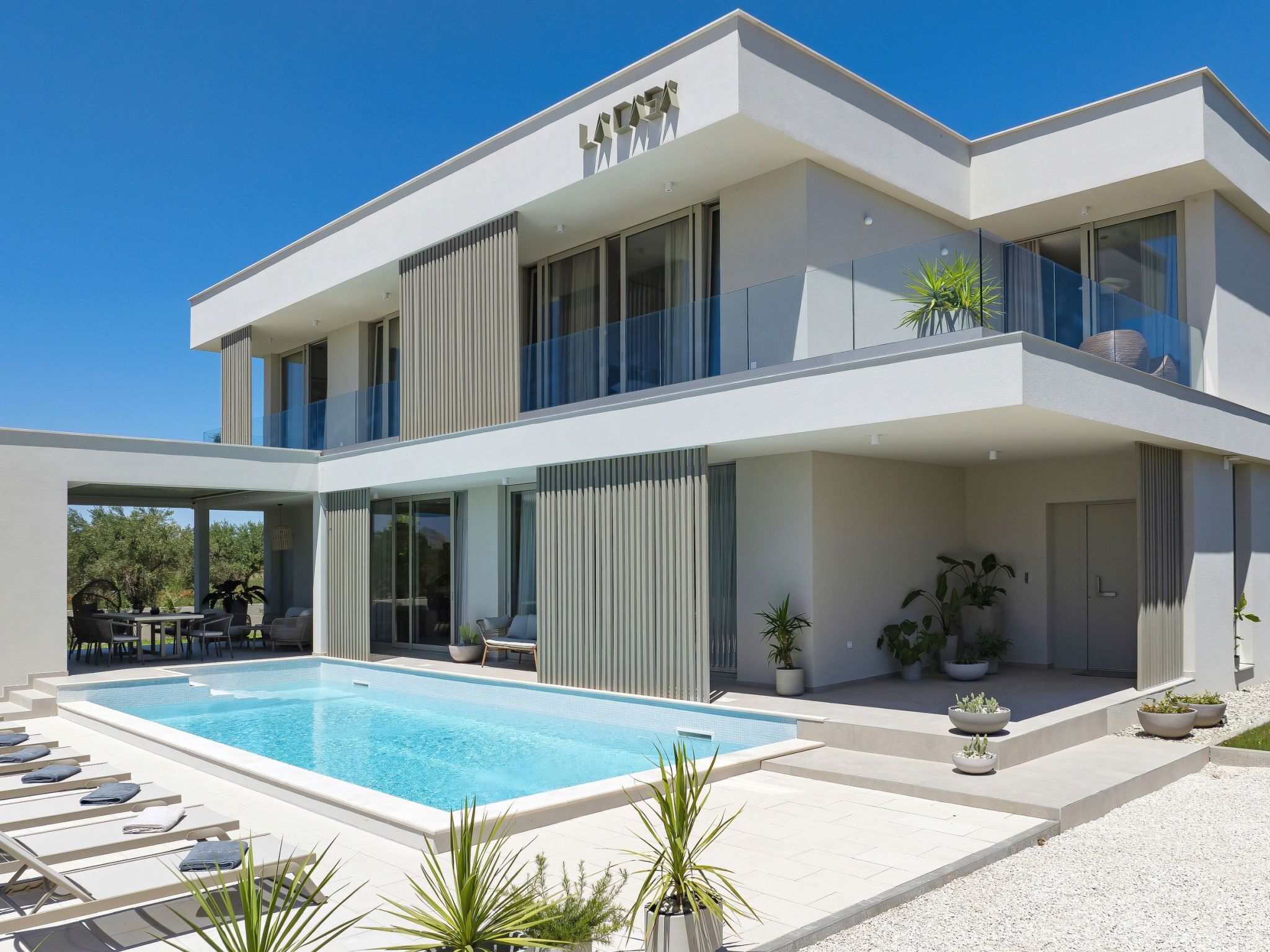 A modern two-story house with a swimming pool, outdoor seating, and potted plants.