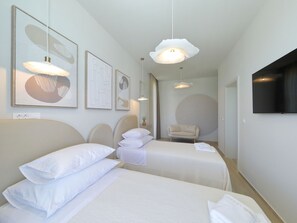 Ein Hotelzimmer mit zwei Betten, einem Sessel und Bildern an den Wänden.