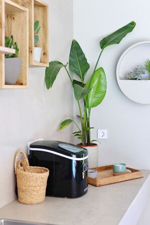 Eine Küche mit Kaffeemaschine, einer Pflanze und einem kleinen Tisch mit einer Tasse.