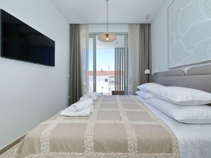 A hotel room with a bed, a TV mounted on the wall, a view through the window, and a ceiling light. - 5* Luxury villa La Casa with heated pool and sauna by Interhome (Zadar/Bibinje)