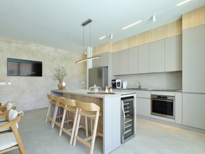 Eine moderne Küche mit einer zentralen Kochinsel, Barhocker, integriertem Backofen und Mikrowelle.
