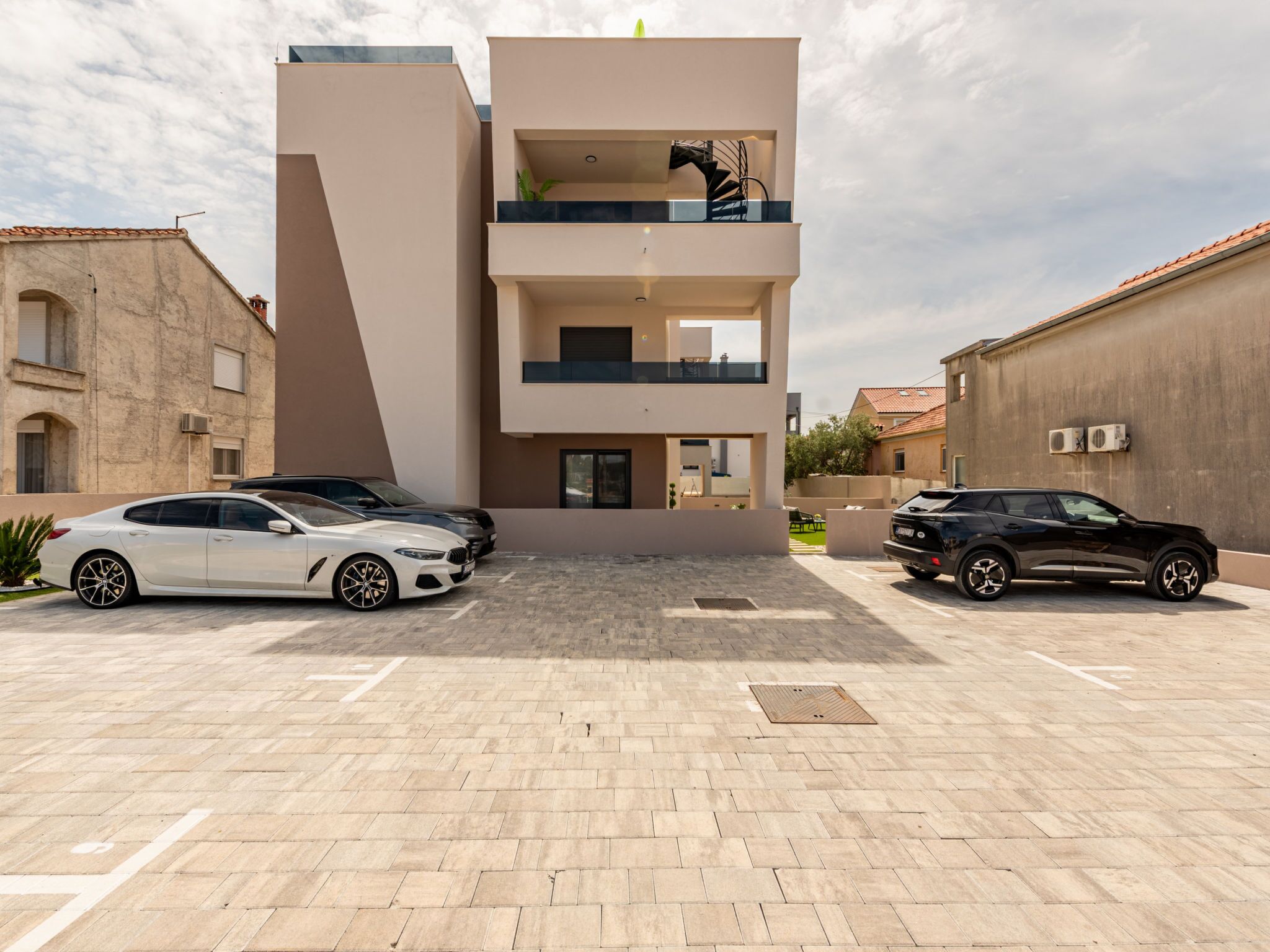 A modern multi-story building with a parking area in front.
