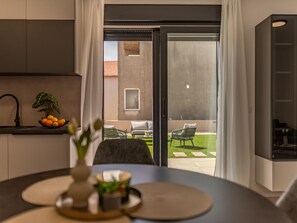 A modern kitchen with a dining area, a view of the outdoor patio, and a sliding glass door leading to the outside. - Apartment  by Interhome (Zadar)