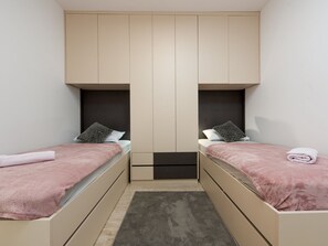 Ein Schlafzimmer mit zwei Betten, einem zentralen Kleiderschrank und einem kleinen Teppich.