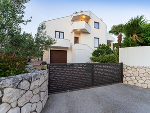 Une maison moderne à deux étages, dotée d’un mur en pierre et d’un portail en métal.