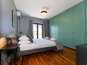 Une chambre à coucher avec un lit, une lampe de chevet, une fenêtre avec des rideaux et une armoire.