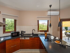 A modern kitchen with a built-in microwave, coffee maker, and a sink. - Seaview Villa Tia with pool by Interhome (Zadar)