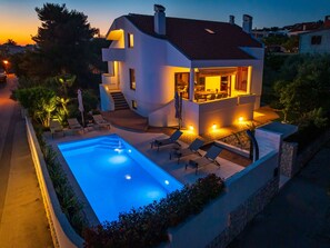 A modern two-story house with a swimming pool, outdoor seating, and a well-lit patio area. - Seaview Villa Tia with pool by Interhome (Zadar)