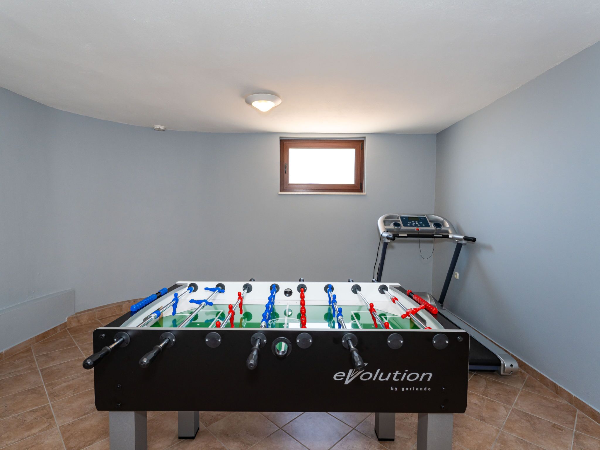 Une pièce équipée d’un baby-foot et d’un tapis de course.