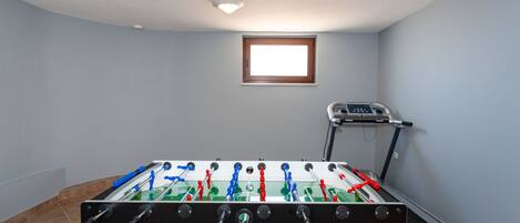 Una habitación con mesa de fútbol y cinta de correr.