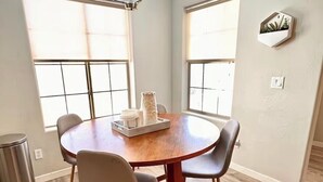 A dining area with a round table, four chairs, a chandelier, and large windows. - Surprise tropical oasis with private heated pool! (Surprise)