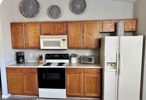 Eine Küche mit Holzschränken, einer Mikrowelle, einem Herd, einem Kühlschrank und einem Toaster.